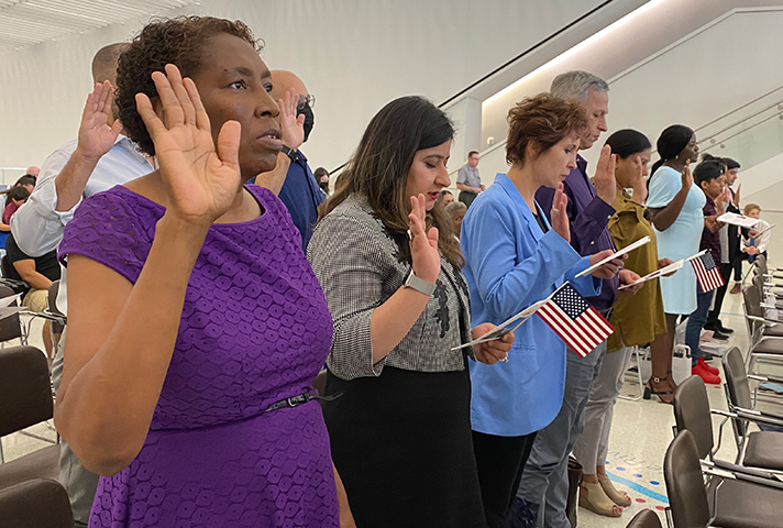 New citizens recite the Oath of Allegiance during a naturalization ceremony at the Gateway Arch National Park in St. Louis.